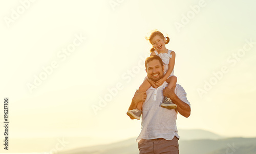 father's day. child daughter sits on her dad shoulders outdoors on a summer .