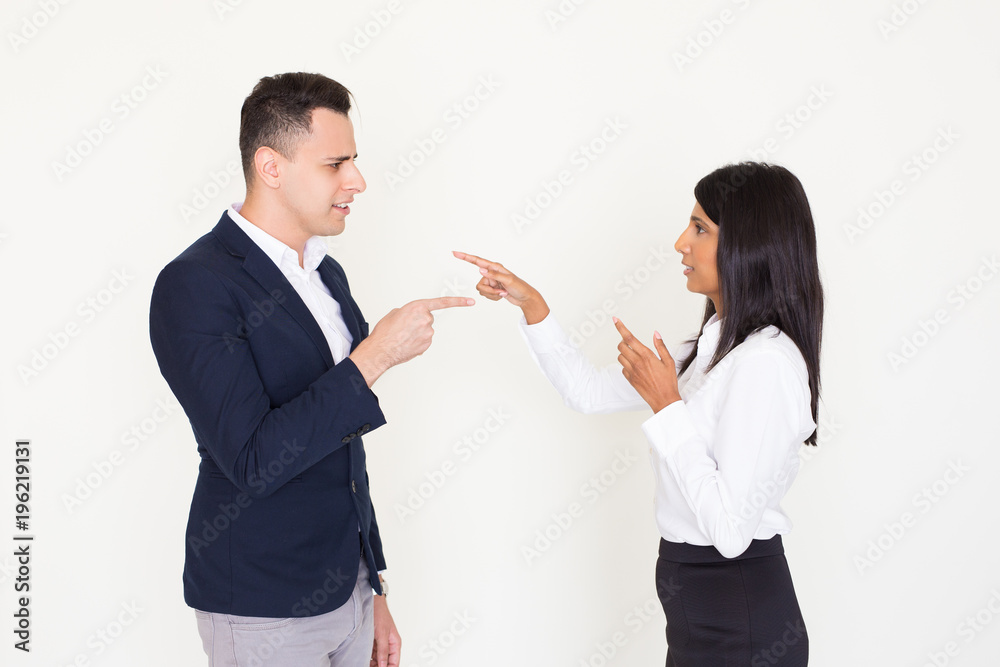 Displeased young colleagues accusing each other Displeased young colleagues accusing each other