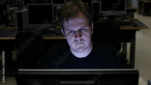 Male using computer in dark room or computer lab.
 photo