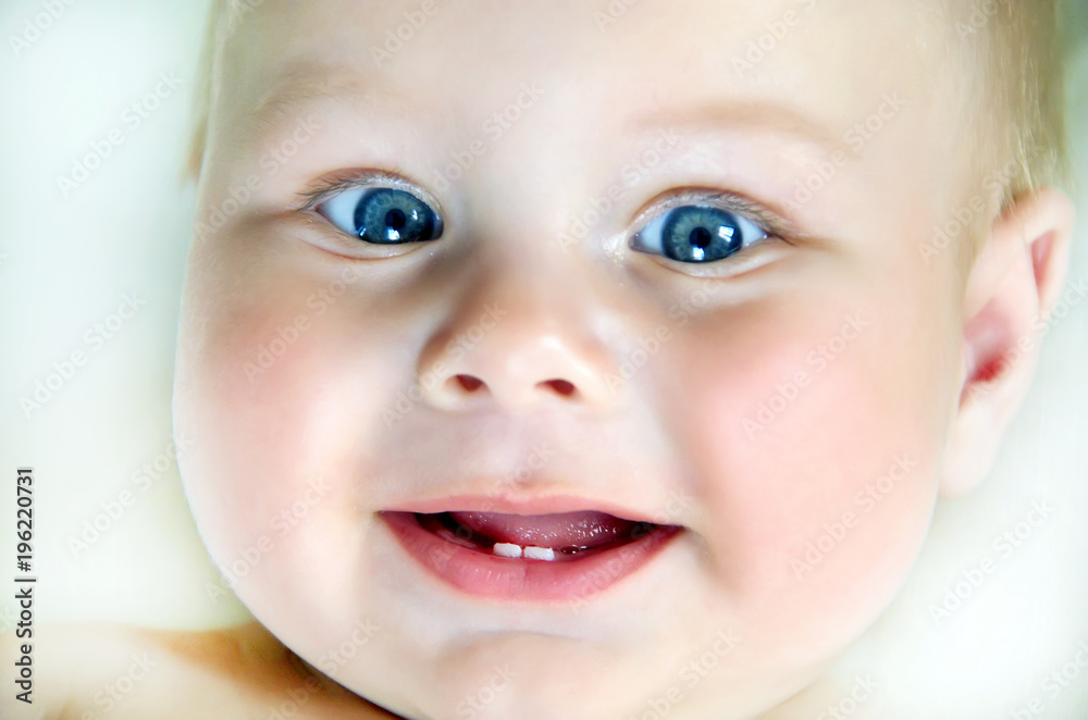 Close up of adorable 6 months old baby with first teeth looking at camera Close up of adorable 6 months old baby with first teeth looking at camera