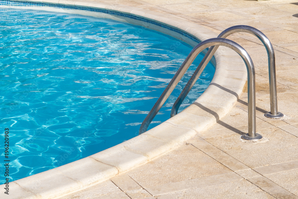 pool with blue water and stairs outside in a sunny day