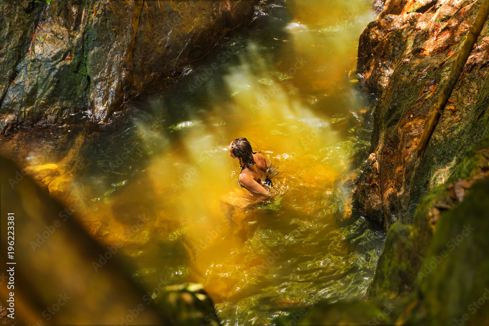 Obraz premium Young woman swimming in a natural tropical pool