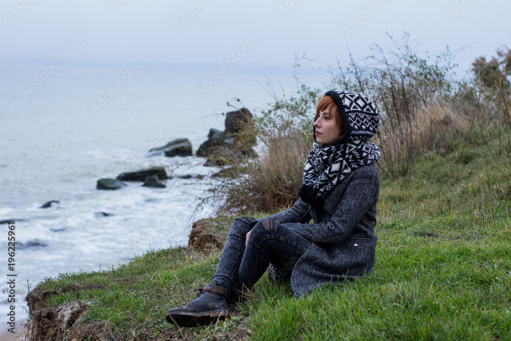 Young woman in grey coat against the autumn sea background Young woman in grey coat against the autumn sea background