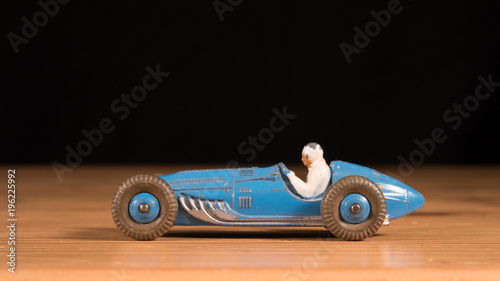 Metal retro toy race car on wooden table with black background