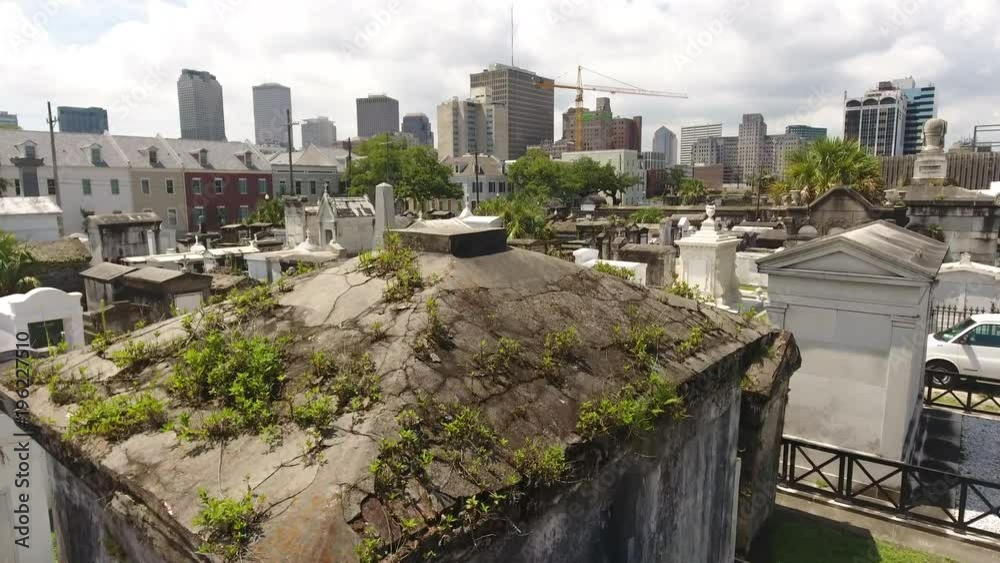 Over Grassy Tomb Towards Downtown Beyond Old And Urban New Orleans Cemetery Over Grassy Tomb Towards Downtown Beyond Old And Urban New Orleans Cemetery
