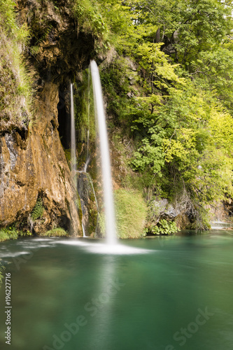 Paradise landscape with waterfall flowing into a pond in Plitvice Lakes National Park in summer in Croatia