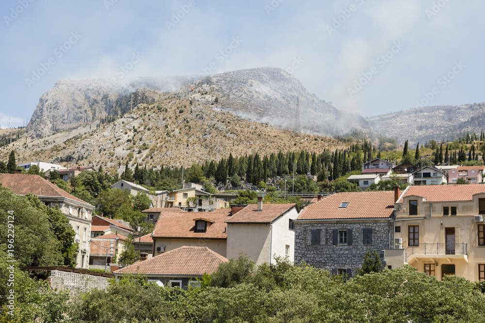 View of the historic old town of Mostar with the mountains in the background where a forest fire rages
