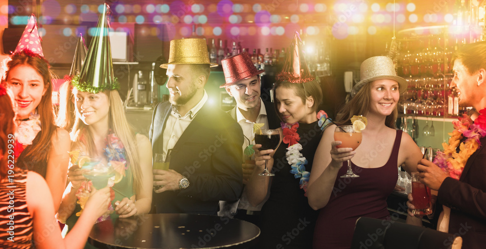 Portrait of young women and men in caps with cocktails