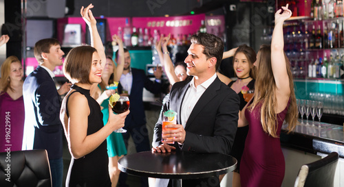 Colleagues dancing on corporate party with cocktails in hands