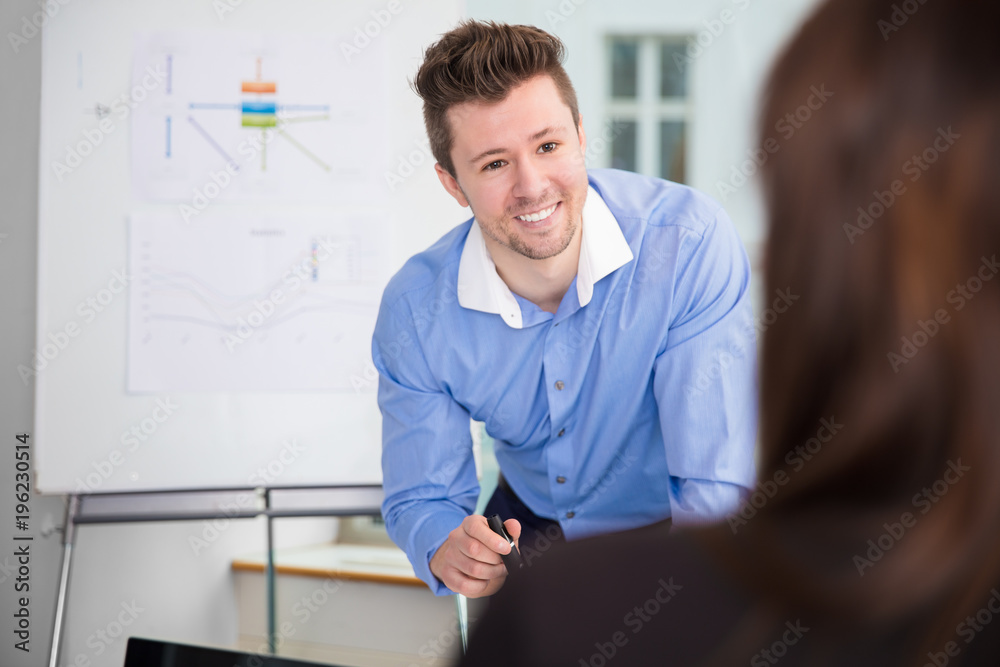 Fototapeta premium Smiling Businessman Looking At Female Colleague In Office