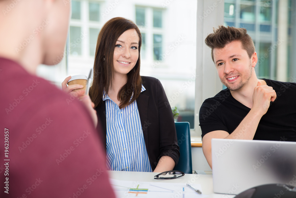Business People Smiling While Looking At Colleague At Desk
