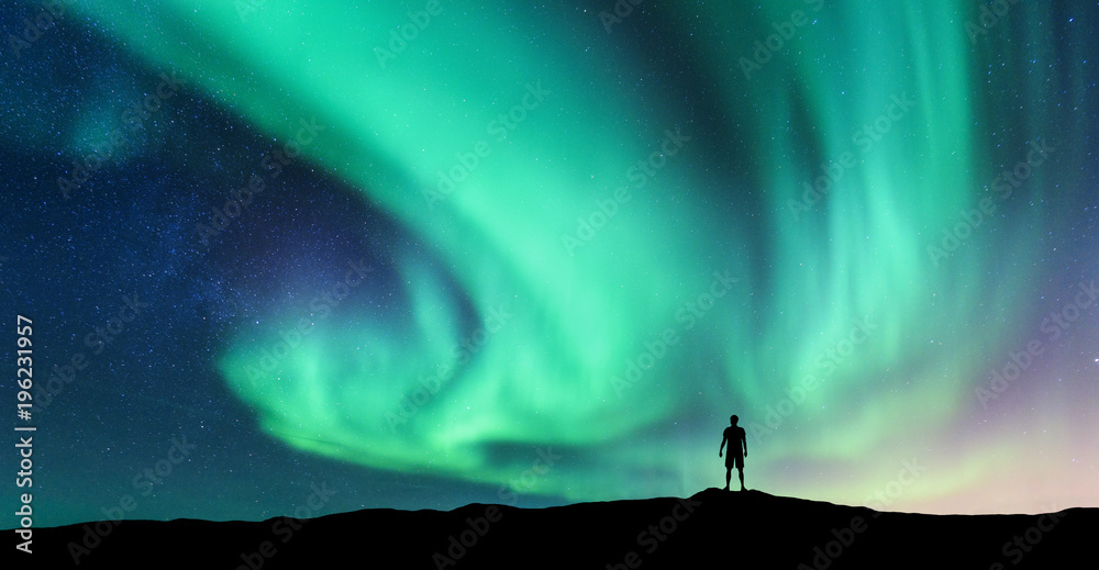 Fotobehang Zeegroen Aurora borealis en silhouet van staande man. Lofoten eilanden, Noorwegen. Aurora en gelukkige man. Hemel met sterren en groene poollichten. Nachtlandschap met aurora en mensen. Concept. Natuur achtergrond #196231957