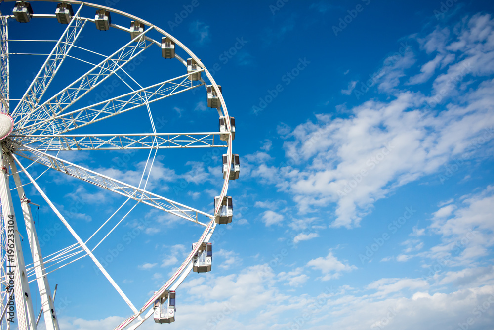 Horizontal View of a White Ferris Wheel on Partially Cloudy Sky Background. Copy Space. Bari, South of Italy Horizontal View of a White Ferris Wheel on Partially Cloudy Sky Background. Copy Space. Bari, South of Italy