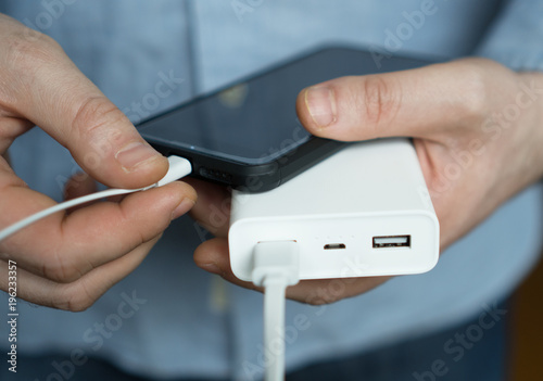 Man charging smartphone with power bank. photo