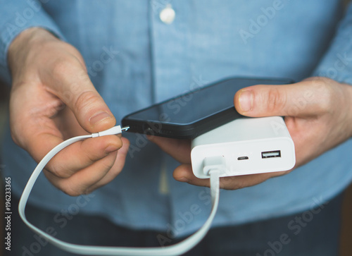 Man charging smartphone with power bank. photo