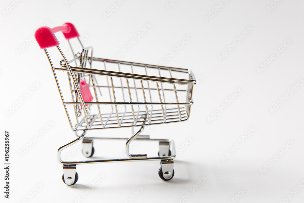 Close up of supermarket grocery push cart for shopping with black wheels and pink plastic elements on handle isolated on white background. Concept of shopping. Copy space for advertisement