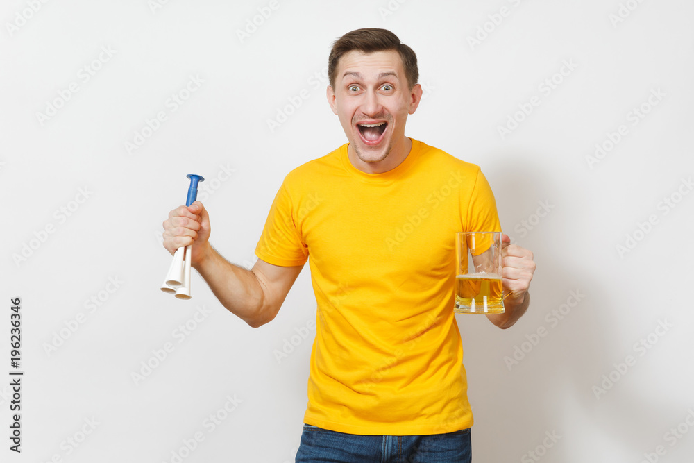 Inspired young fun cheerful European man, fan or player in yellow t-shirt hold pint mug of beer, football pipe cheer favorite team isolated on white background. Sport, student, play lifestyle concept. Inspired young fun cheerful European man, fan or player in yellow t-shirt hold pint mug of beer, football pipe cheer favorite team isolated on white background. Sport, student, play lifestyle concept.