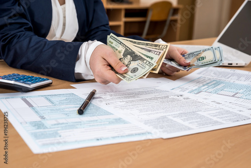 Business lady counts dollars, over the tax form 1040