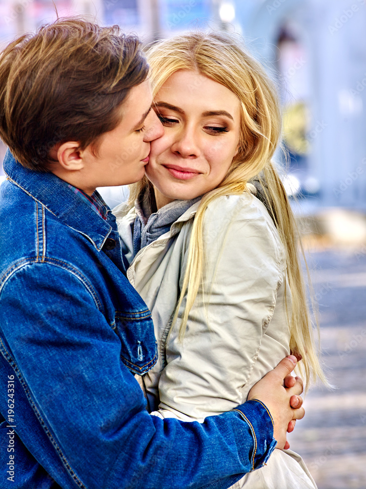 Fototapeta premium Spring couple walking park and kissing. Summer friends walk outdoor. First date of two young people in good weather day. Tone image with backlit shiny background sunset. Meeting after long separation.