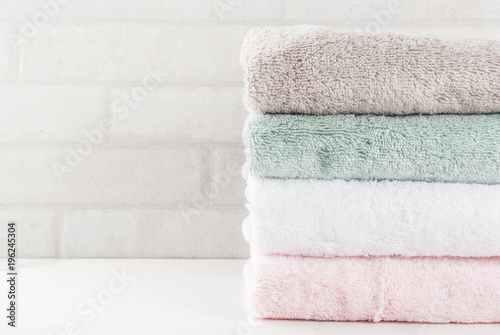 Spa relax and bath concept, stack clean bath towels colorful cotton terry textile in bathroom white background, copy space top view