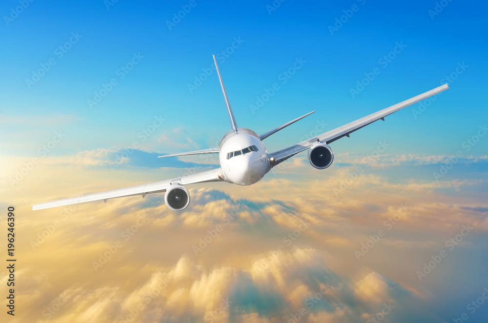 Obraz premium Samolot pasażerski leci z dużą prędkością na niebie ponad chmurami i pomarańczowym zachodem słońca, widok jest dokładnie na kokpicie pilotów.