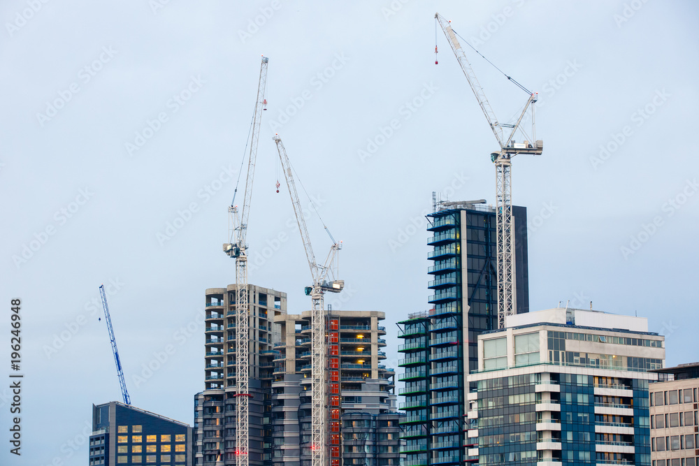 New skyscrapers under construction with tall cranes. Construction business and industry, urbanisation, urban sprawl real estate bubble concept, background with copy space.