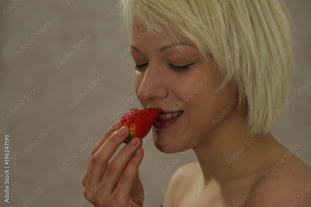 Young blonde girl profile trying the strawberry with joy Young blonde girl profile trying the strawberry with joy