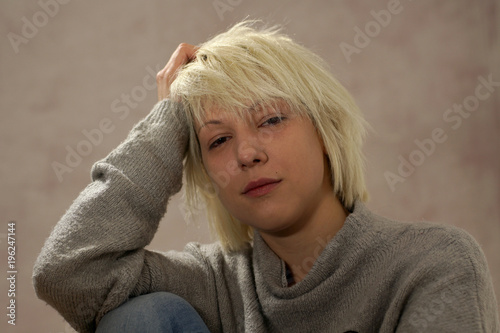 Young blonde girl portrait in a casual mood. She's looking at camera with a friendly gesture.
