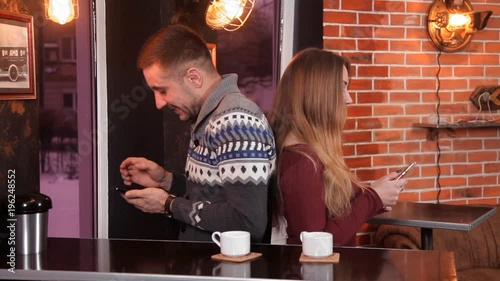 Loving couple drinking coffee in the restaurant and use smartphones photo