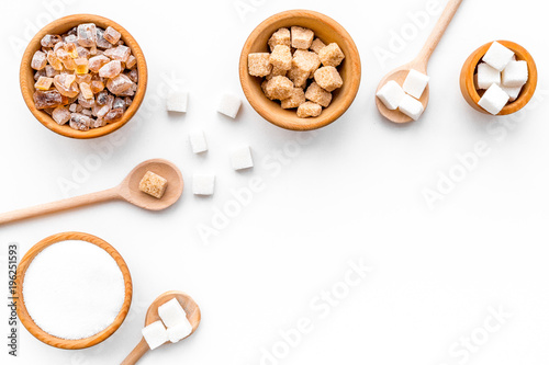 Brown and white sugar in bowls, scoop and spoon. Cane, refind, granulated, cubes, candy. White background top view copy space photo