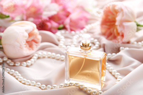 Perfume bottle with roses and bead on satin background