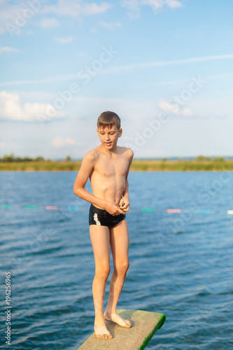 sporty cute young boy jumps very high from pier and having fun on his vacation by the sea