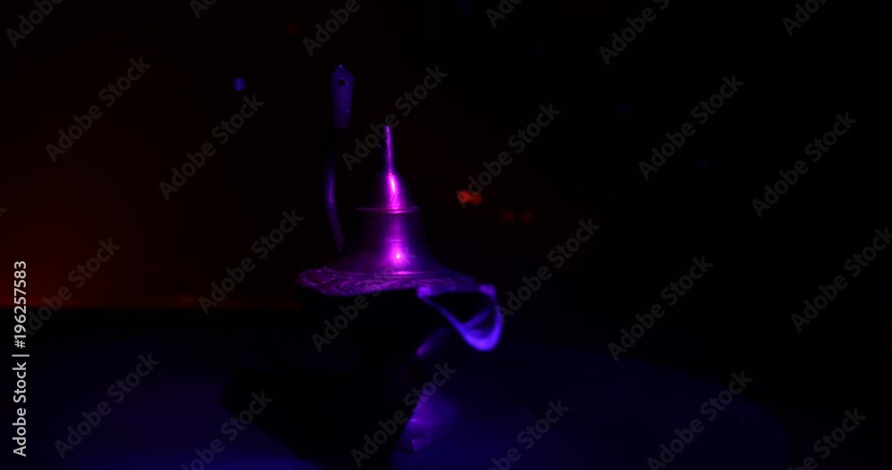 Slider shot.  Antique artisanal Aladdin Arabian nights genie style oil lamp with soft light white smoke. dark smoky toned background. Lamp of wishes