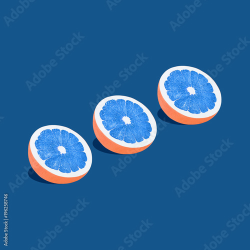 Grapefruit in pop art style Three halves of grapefruit with blue pulp are lying on a blue background Trendy photo with text space