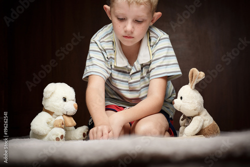 cute little boy reading book with his favorite toys