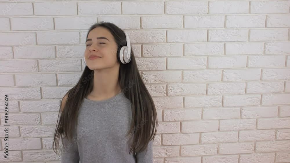 The girl is dancing indoors. The teenager is dancing with headphones. The girl is dancing indoors. The teenager is dancing with headphones.