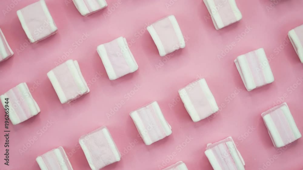 Bright and colorful marshmallows close-up macro shot on a pink background. Rotating Top view.