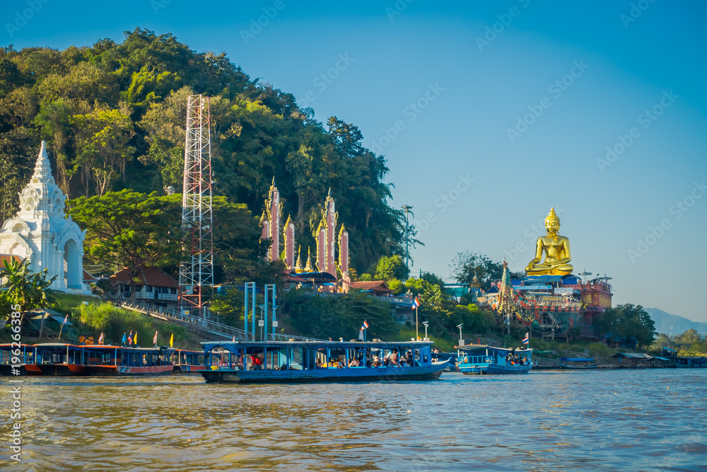 Outdoor view of a group of tourists in a tourist boat visiting the golden budha located at golden triangle Laos Outdoor view of a group of tourists in a tourist boat visiting the golden budha located at golden triangle Laos
