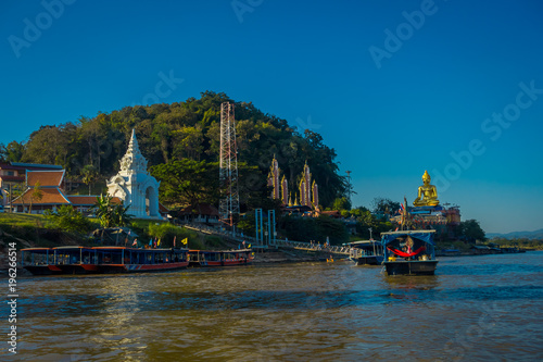 Beautiful outdoor view of a group of tourists in tourist boats visiting the golden budha located at golden triangle Laos