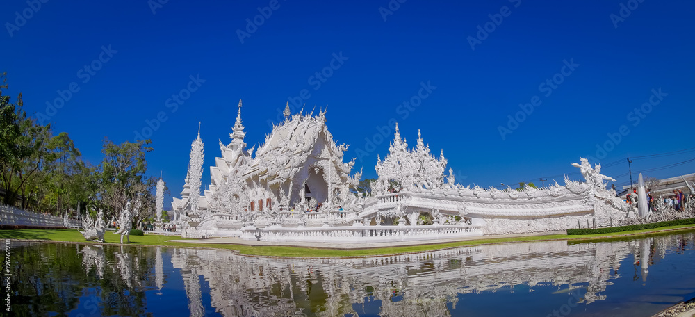 Beautiful panoramic view of white church of Wat Rong Khun temple in Chiangrai, Thailand, reflected in the water