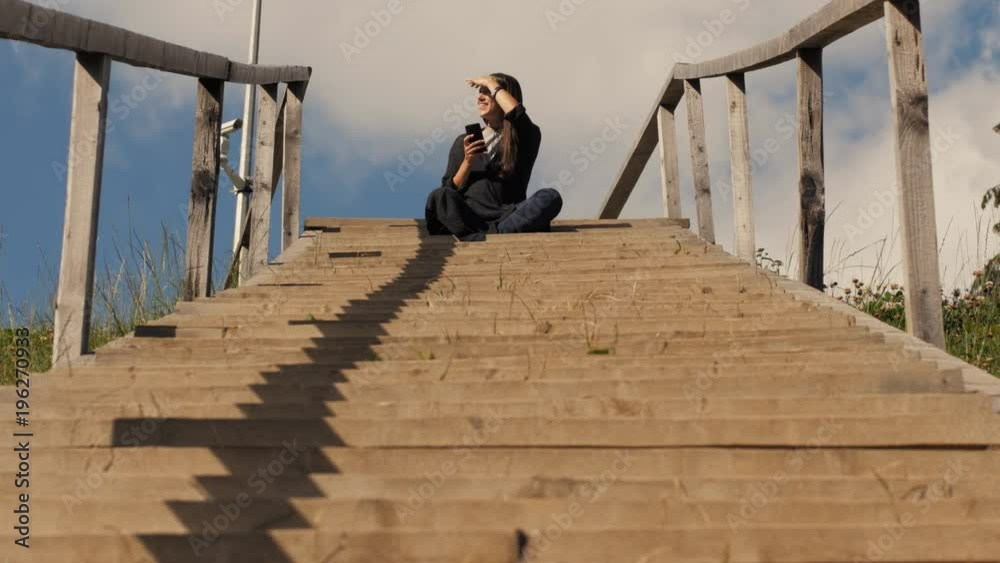 Pregnant female texting on phone while sitting on stairs Pregnant female texting on phone while sitting on stairs