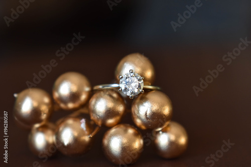 Close up diamond engagement ring resting on golden balls