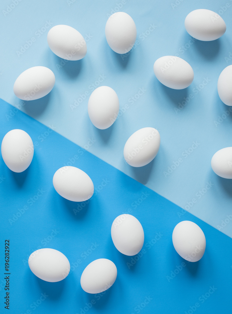 White raw chicken eggs on colorful blue background White raw chicken eggs on colorful blue background