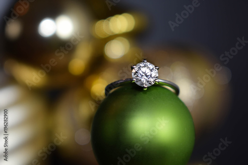 Close up of a diamond engagement ring resting on a Christmas ornament