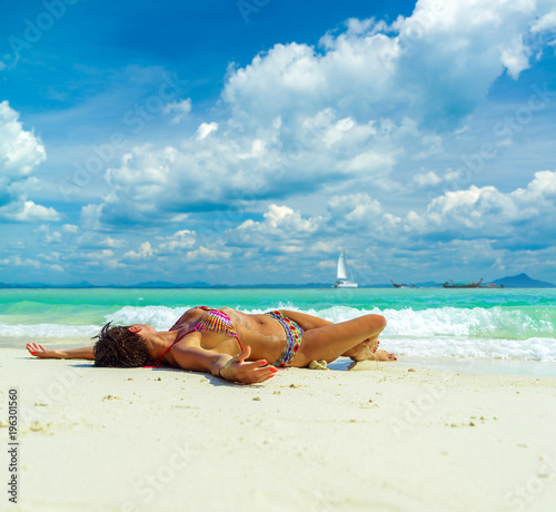 Fototapeta Naklejka Na Ścianę i Meble -  Cute woman relaxing on the summer tropical beach.  White sand, blue sky and crystal sea of tropical beach. Vacation in Paradise. Ocean beach relax, travel to islands