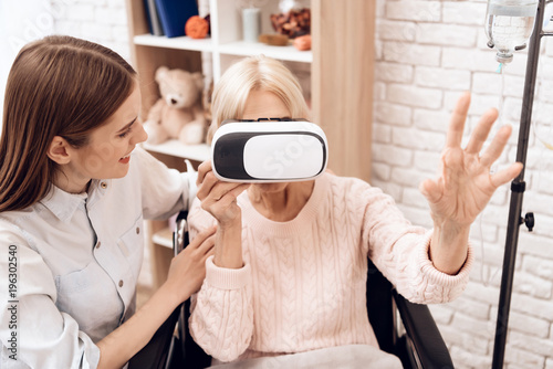 Girl is caring for elderly woman at home. Woman is using virtual reality. © freeograph