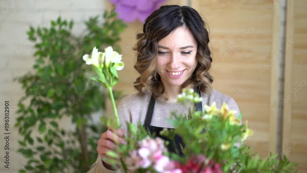 Florist at work: pretty young blond woman holds fashion modern bouquet of different flowers with peone and roses in craft paper Florist at work: pretty young blond woman holds fashion modern bouquet of different flowers with peone and roses in craft paper