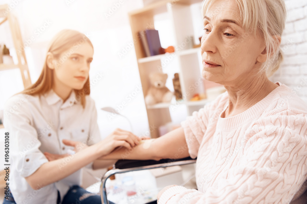 Obraz premium Girl is nursing elderly woman at home. Girl is using drop counter to help woman.