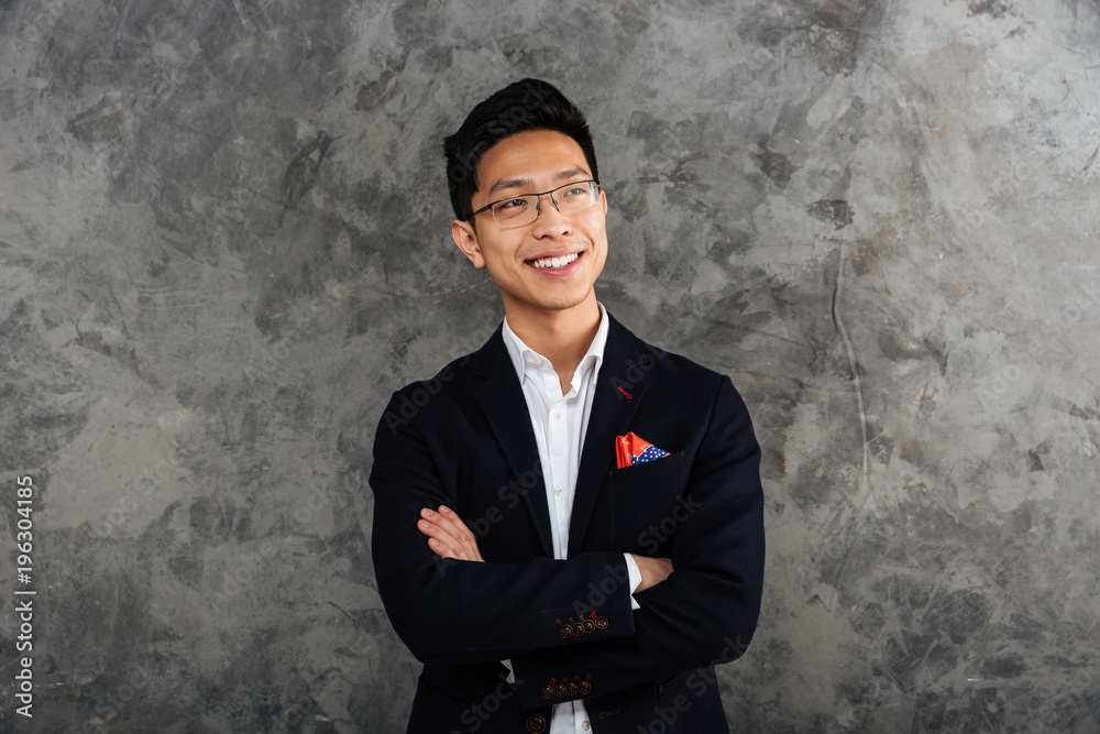 Portrait of a smiling asian man dressed in suit standing Portrait of a smiling asian man dressed in suit standing