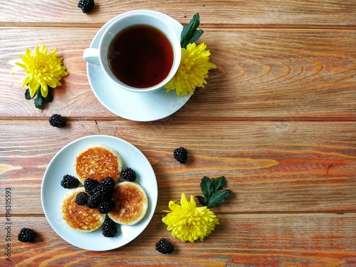 BlackBerry and pancake on aged wooden background with flowers and coffee